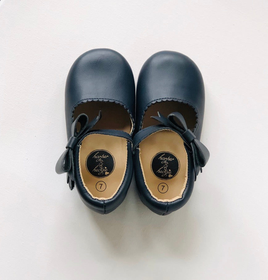 Navy leather baby Mary Janes with strap and bow, tan interior.