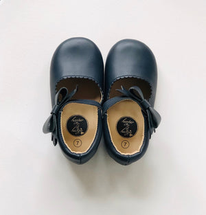 Navy leather baby Mary Janes with strap and bow, tan interior.