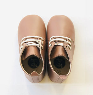 Light brown leather baby shoes with white laces and  displayed side by side on white background.