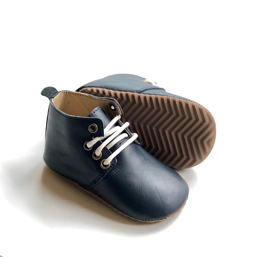 Dark navy baby oxfords with white laces and tan zigzag sole – stylish soft-soled shoes for early walkers