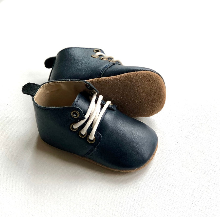 Pair of navy blue leather baby shoes with soft brown soles – flexible and elegant footwear for infants