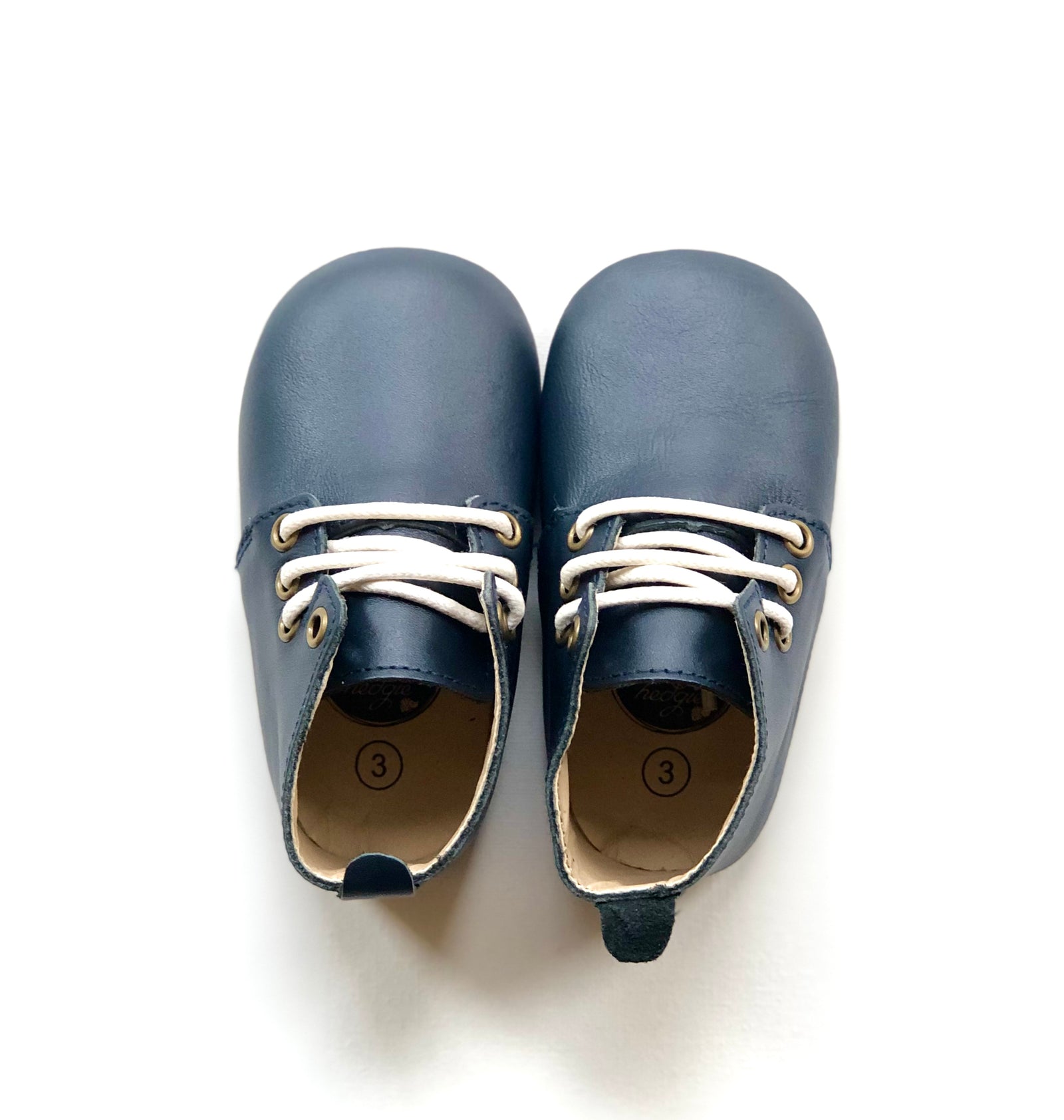 Pair of navy blue leather baby shoes with white laces, size 3, placed side by side on a white background—evoking timeless style, softness, and early childhood essentials.