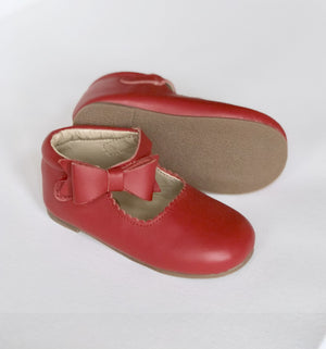 Red baby shoes with scalloped edges, side bow, and soft beige sole, shown upright and side view for detail.