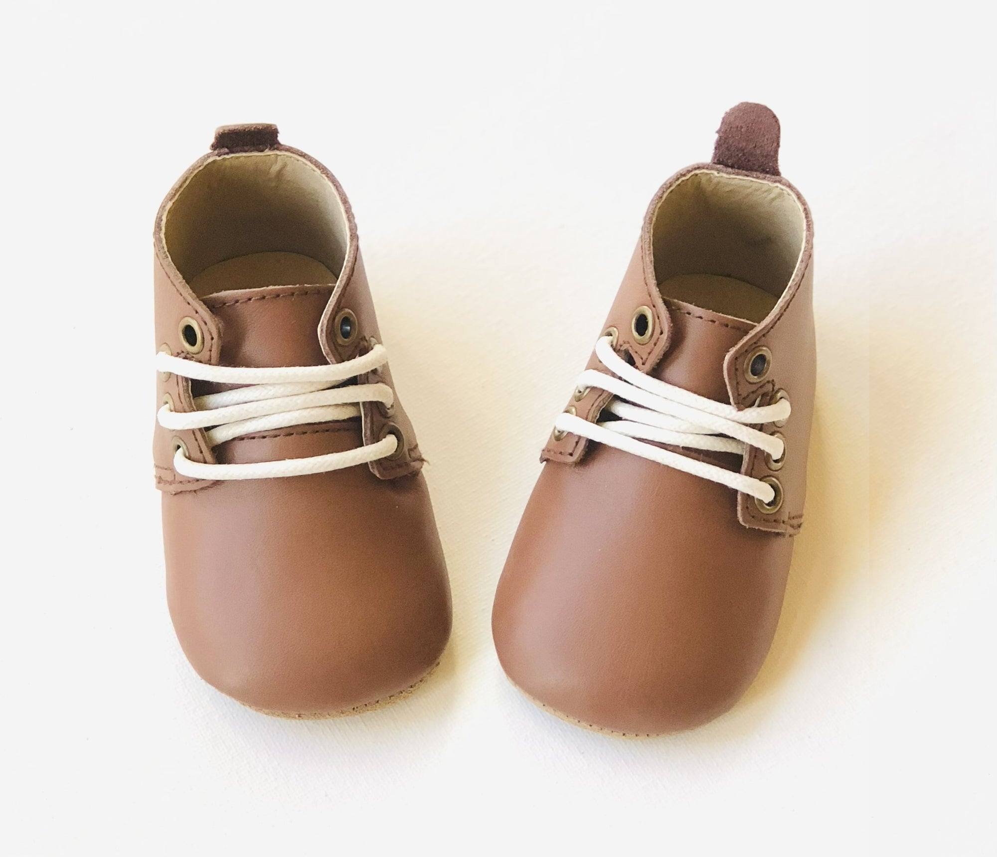 Brown leather infant Oxford shoes with white laces.