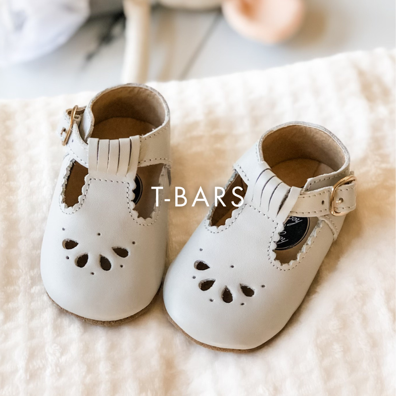 Pair of white baby shoes with T-bars on a soft surface