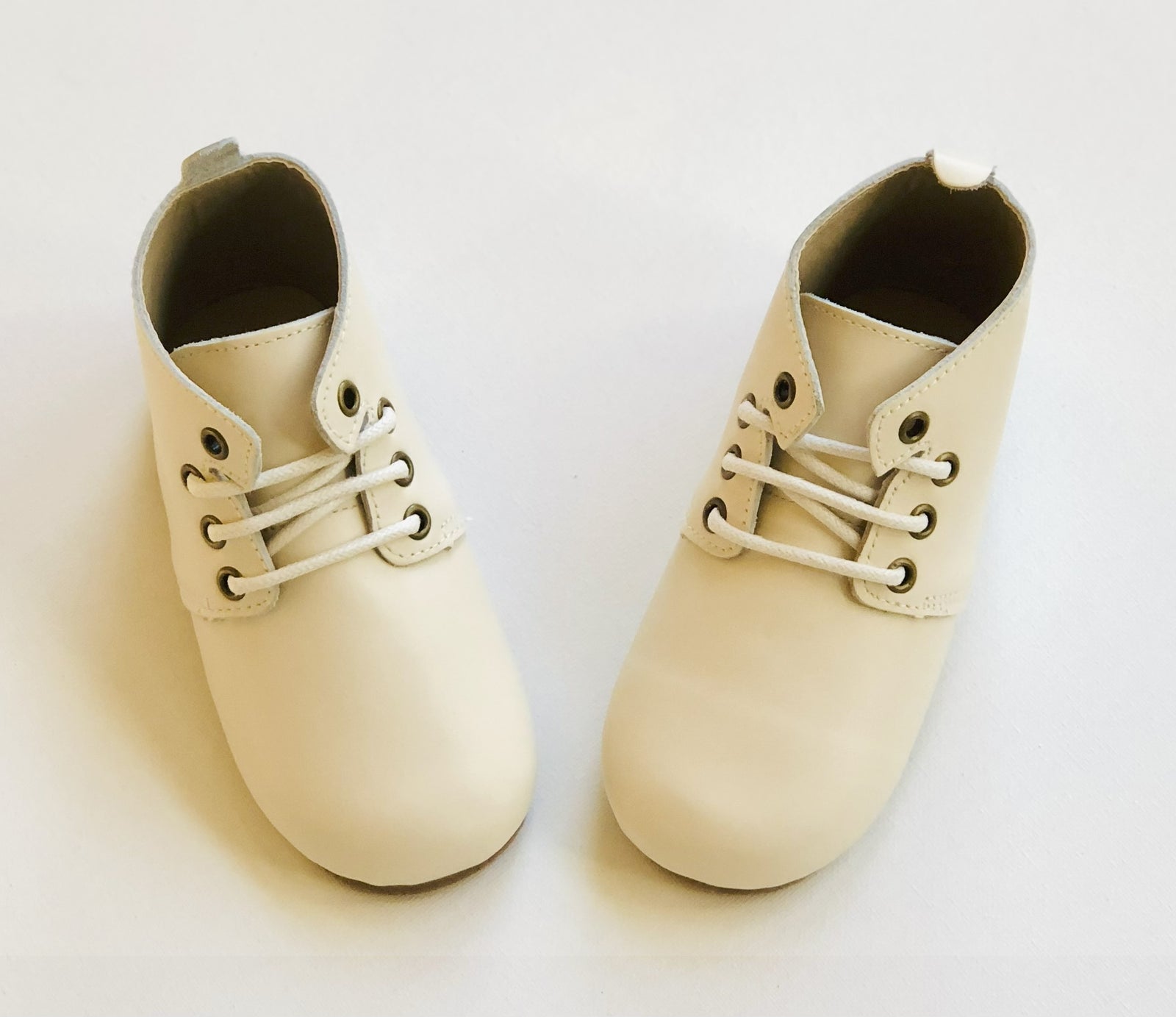 Cream leather baby Oxford shoes with white laces and rounded toes, displayed on white background for product clarity.