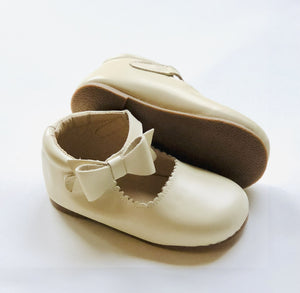 Cream Mary Janes with textured sole and scalloped edges, shown upright and side view for product detail.