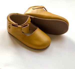 Mustard yellow baby shoes with textured brown sole and scalloped edges, shown upright and side view for detail.