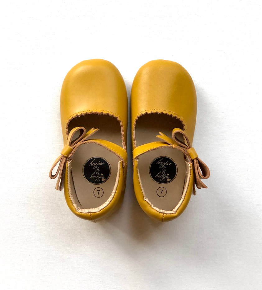 Harper & Hedgie mustard Mary Janes with bow detail and size label, displayed on white background for product clarity.