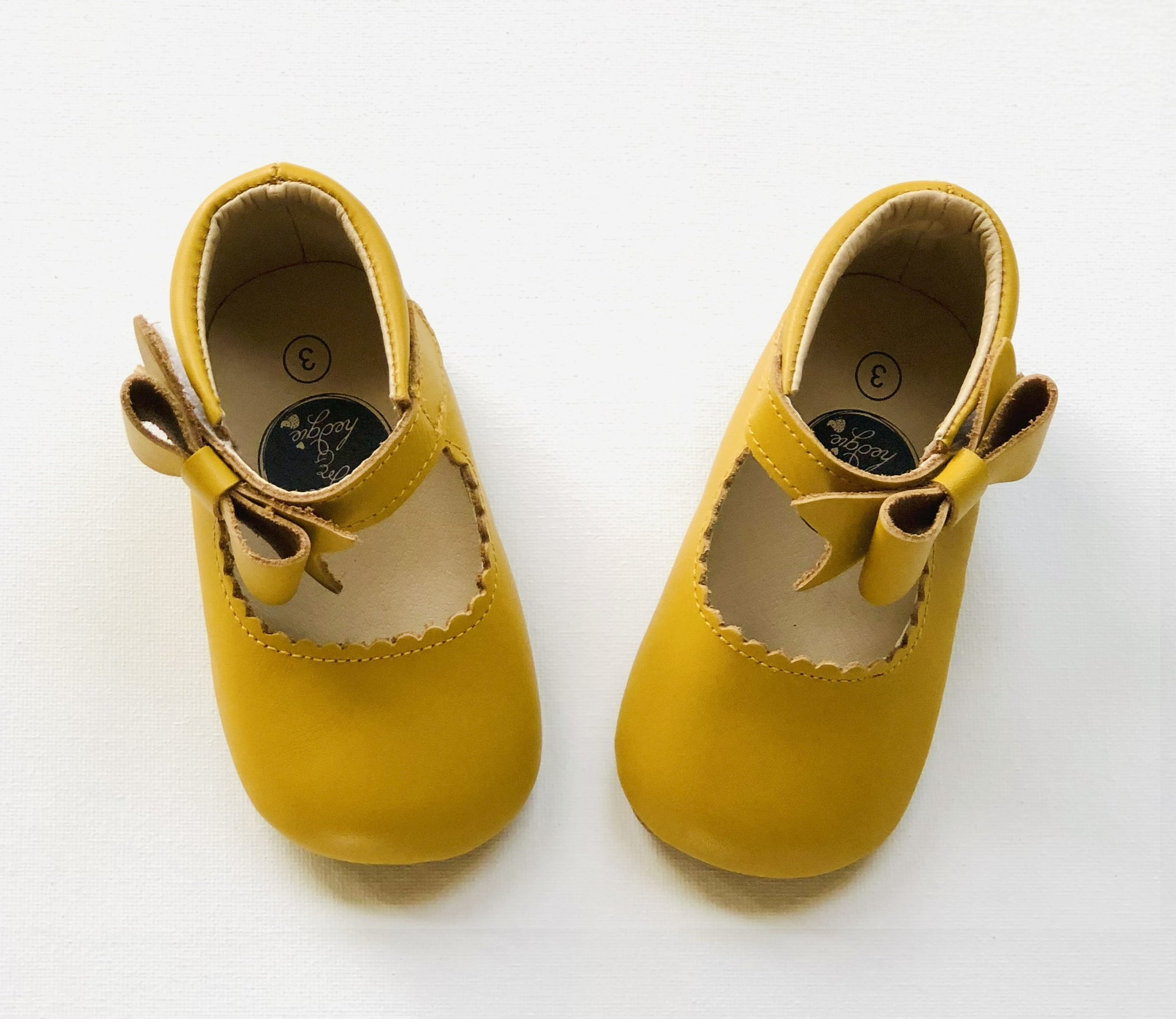 Sweet yellow toddler Mary Jane shoes with scalloped trim, front bow detail, and “size 3” insole label, perfect for special occasions or everyday charm.